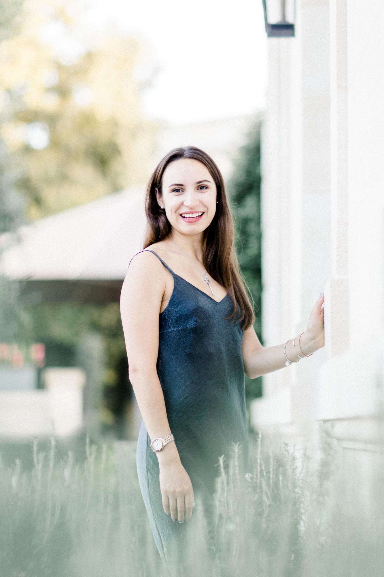 Femme en robe nuisette bleu nuit souriant dans le jardin d'un hôtel particulier bordelais