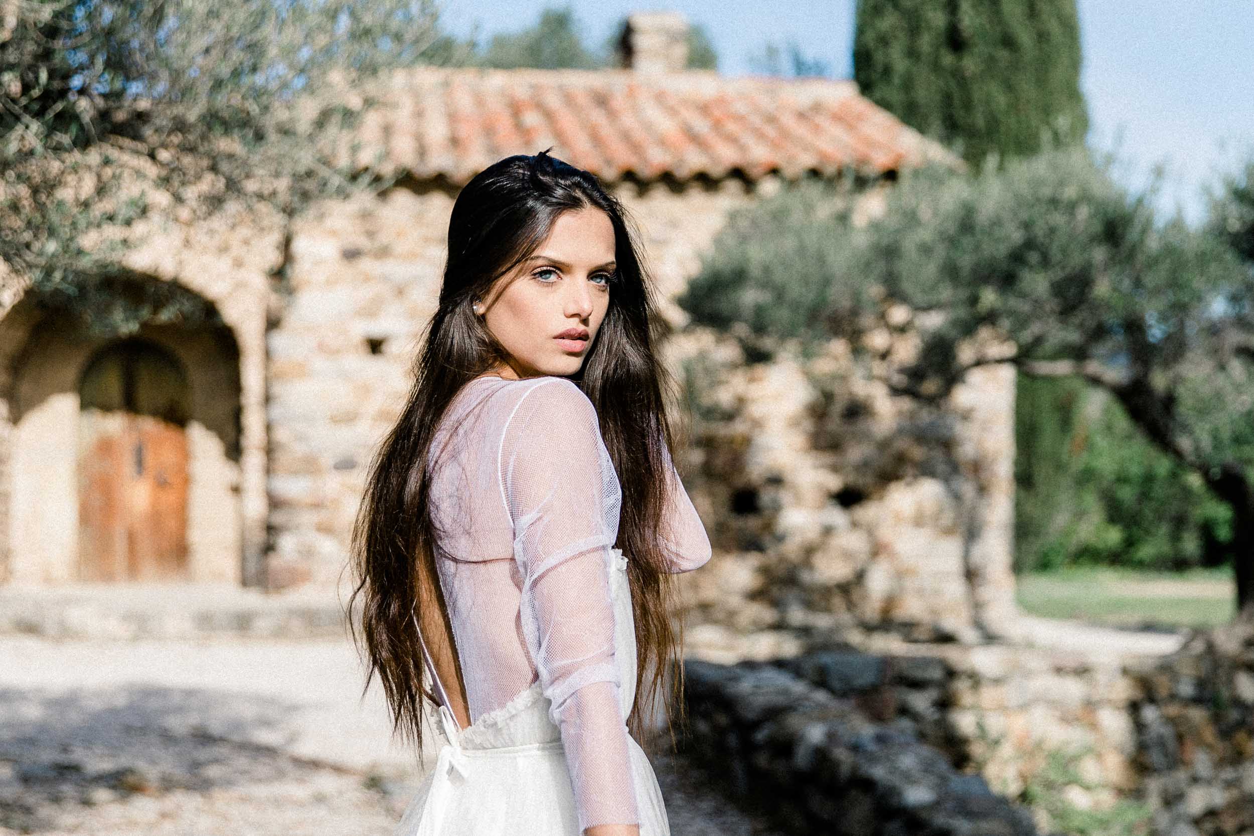 Femme en robe légère devant une maison en pierre ancienne, séance fine art