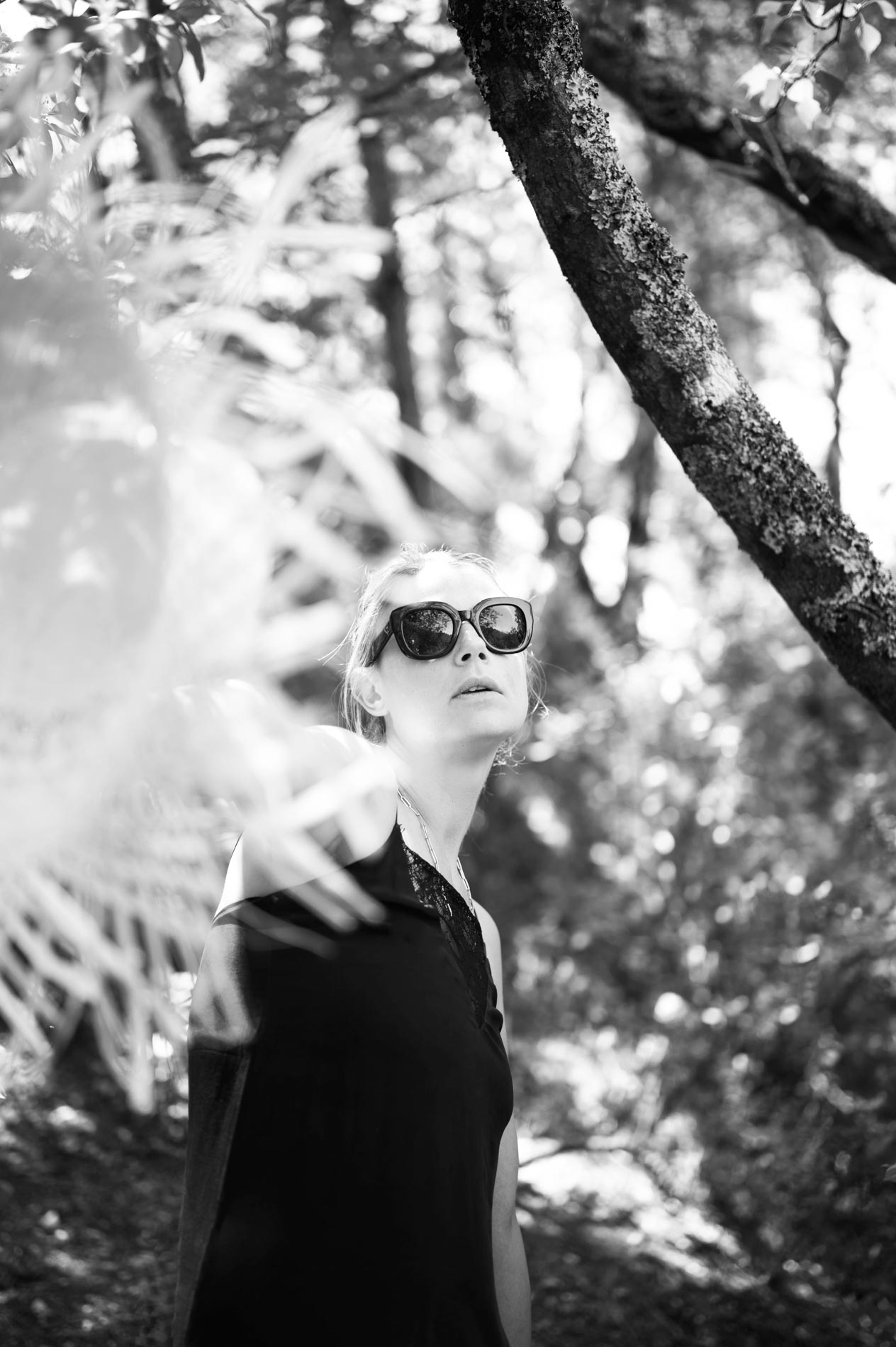 Mannequin en lunettes de soleil et haut noir sous les arbres, en noir et blanc