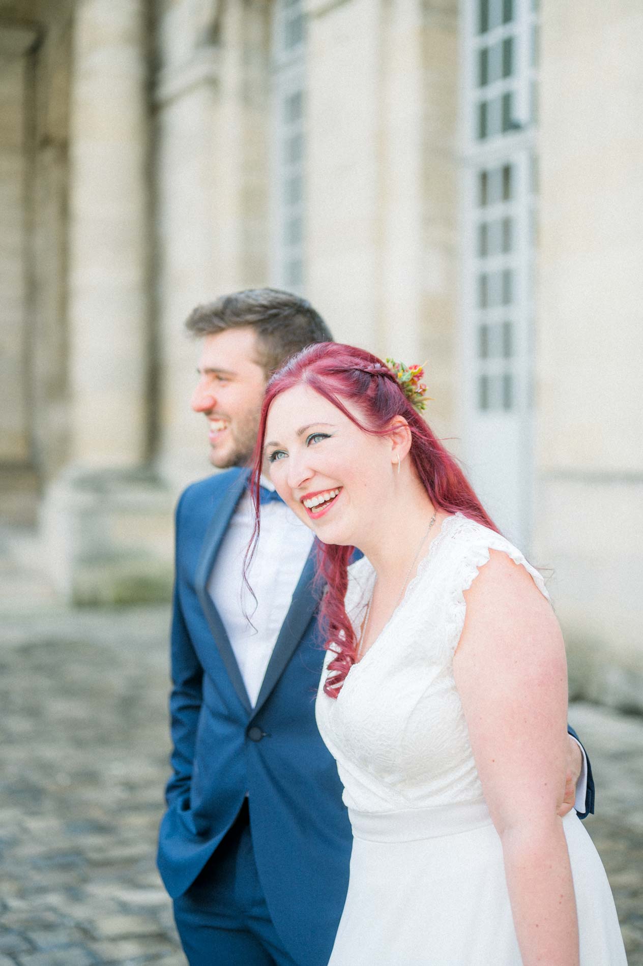 Mariée aux cheveux rouges riant blottie contre le marié