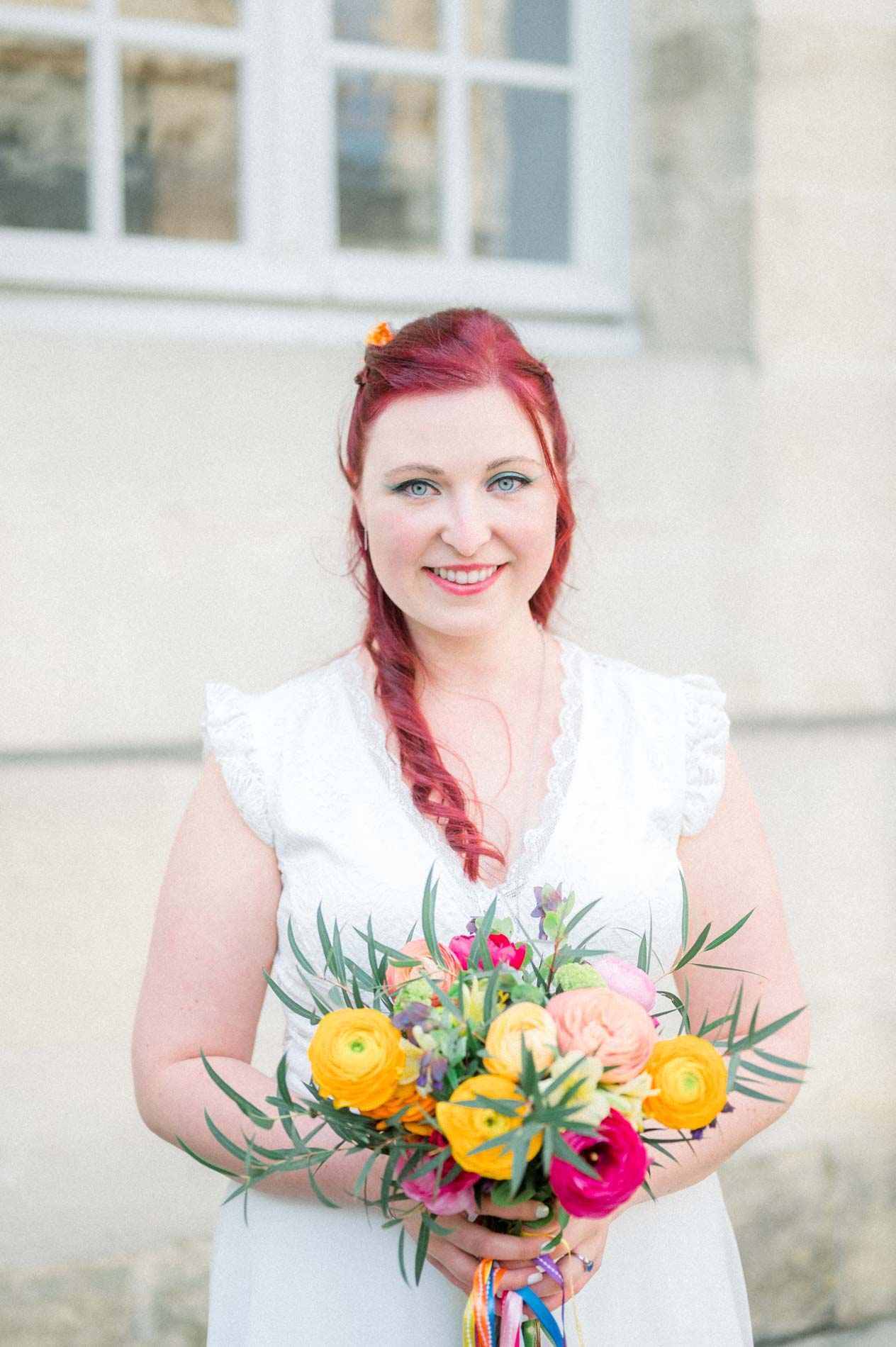 Mariée souriante et son bouquet de renoncules orange et roses