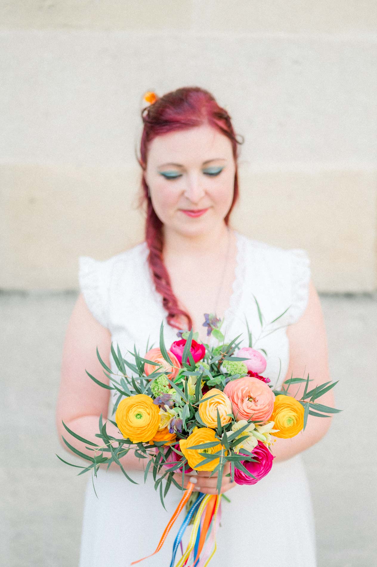 Mariée les yeux baissés vers son bouquet aux couleurs vives