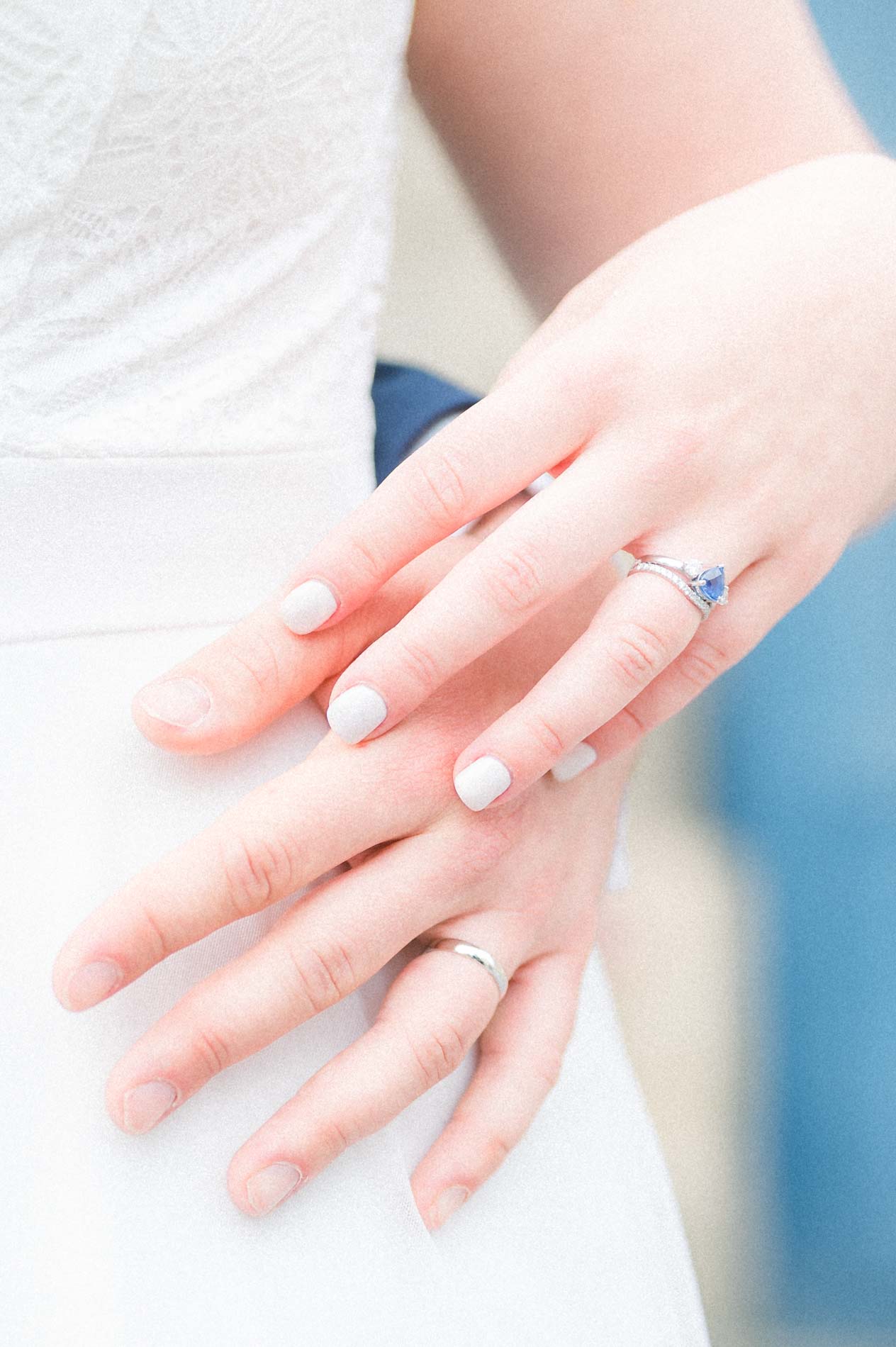 Mains des mariés superposées montrant alliance et bague de fiançailles