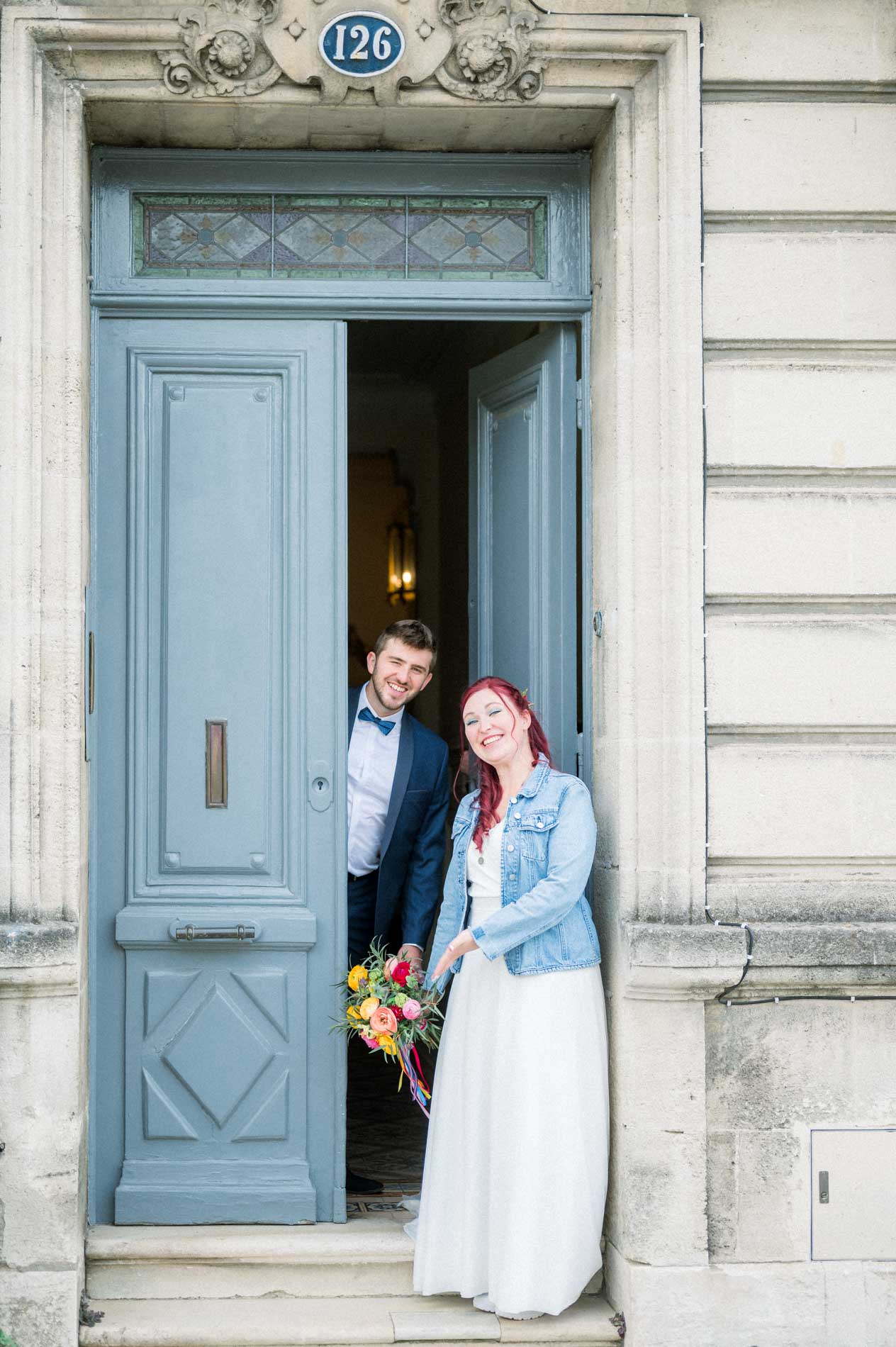 Mariés souriants dans l'encadrement d'une grande porte bleue en ville