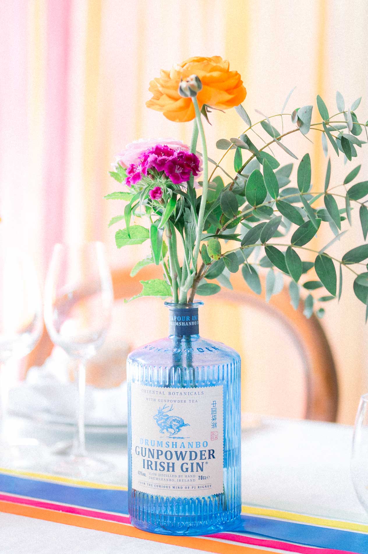 Renoncule orange et anémone dans une bouteille en verre bleu