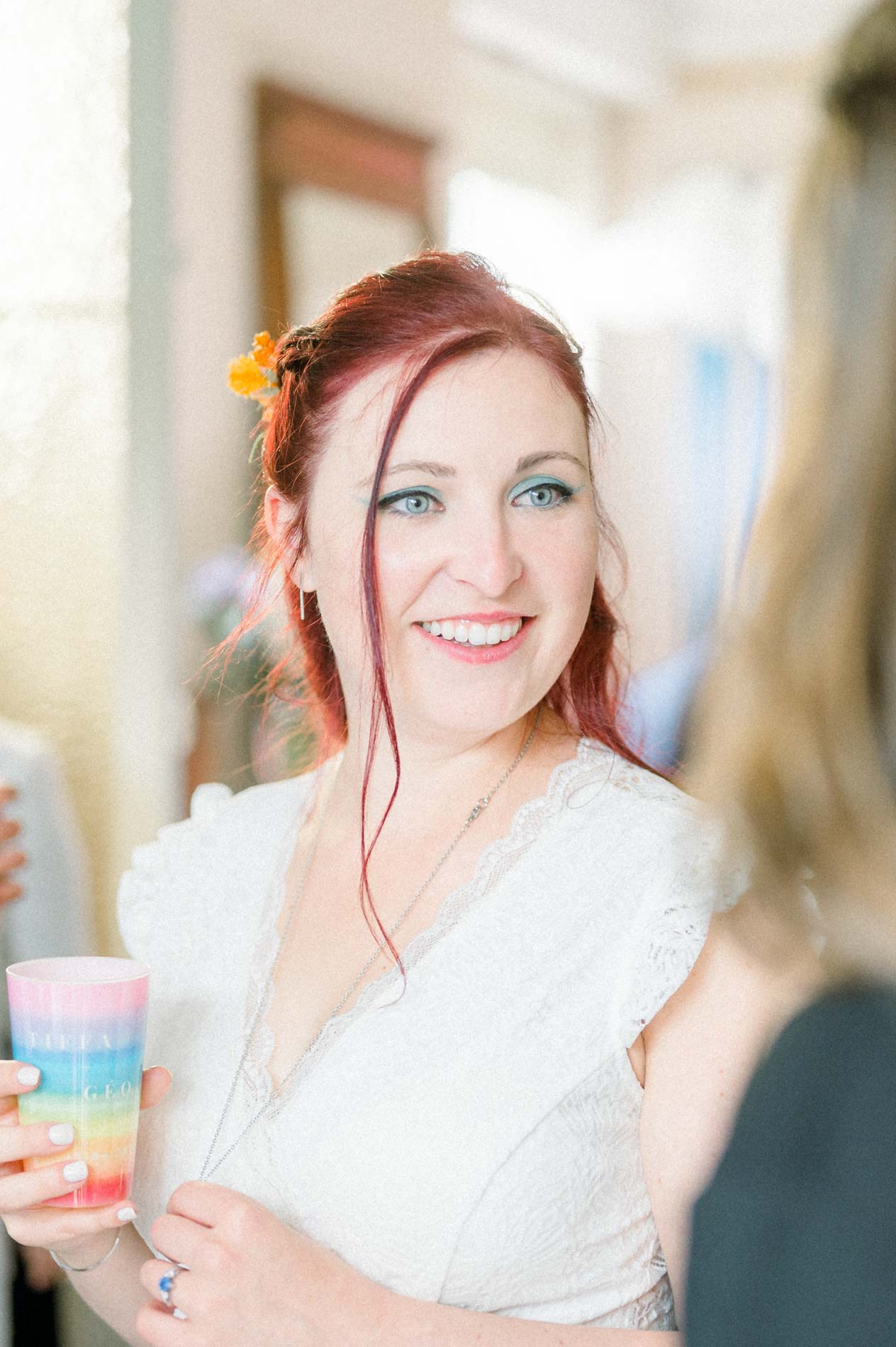 Mariée souriante tenant un gobelet arc-en-ciel pendant la réception