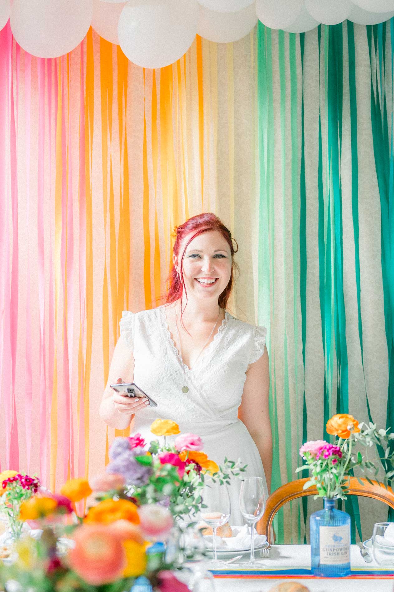 Mariée devant un rideau de rubans multicolores et une table fleurie