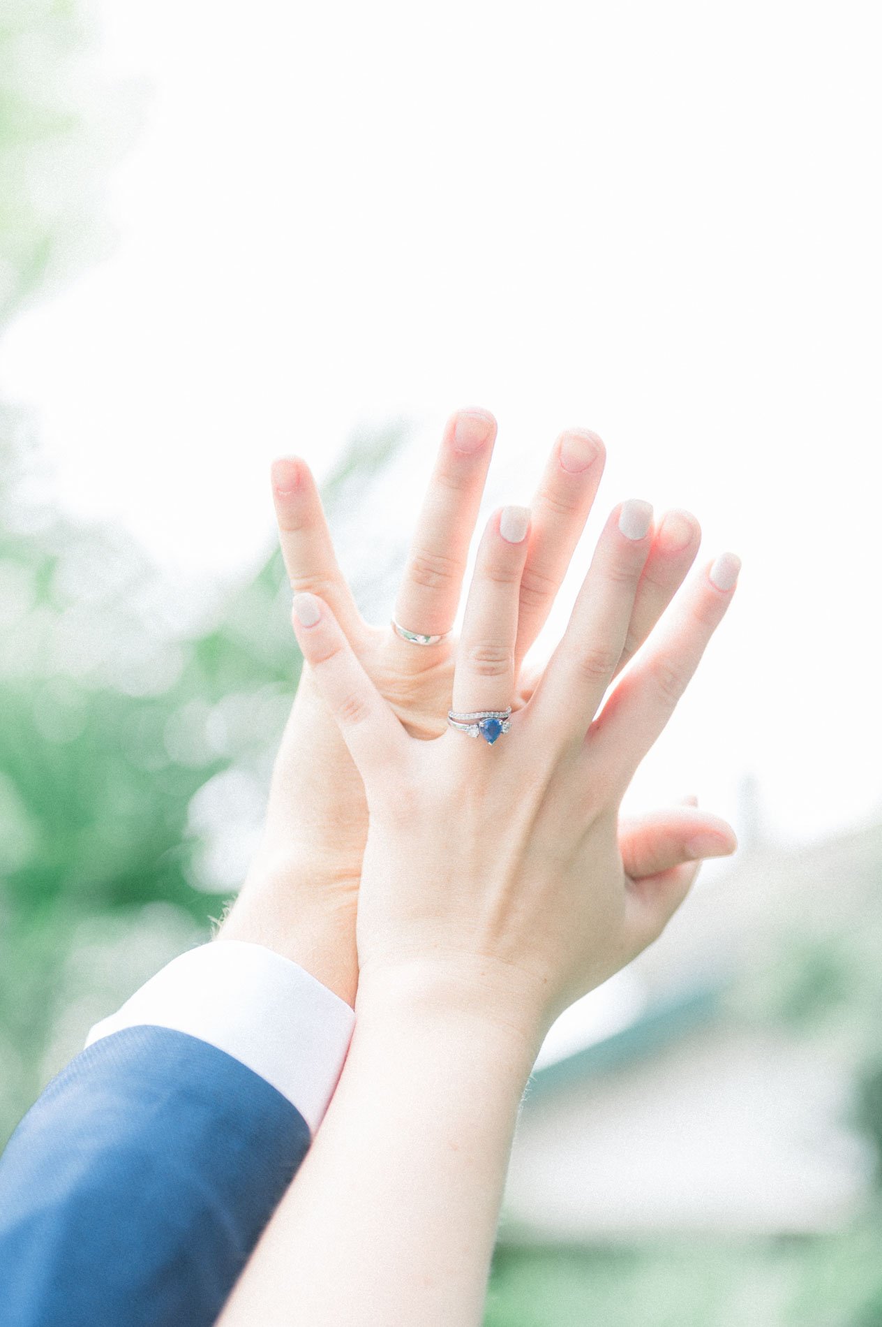 Mains des mariés se touchant avec la bague de fiançailles en saphir