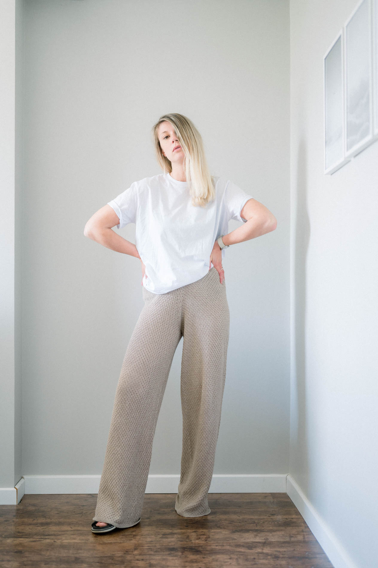 Mannequin en tee-shirt blanc et pantalon large beige, mains sur les hanches