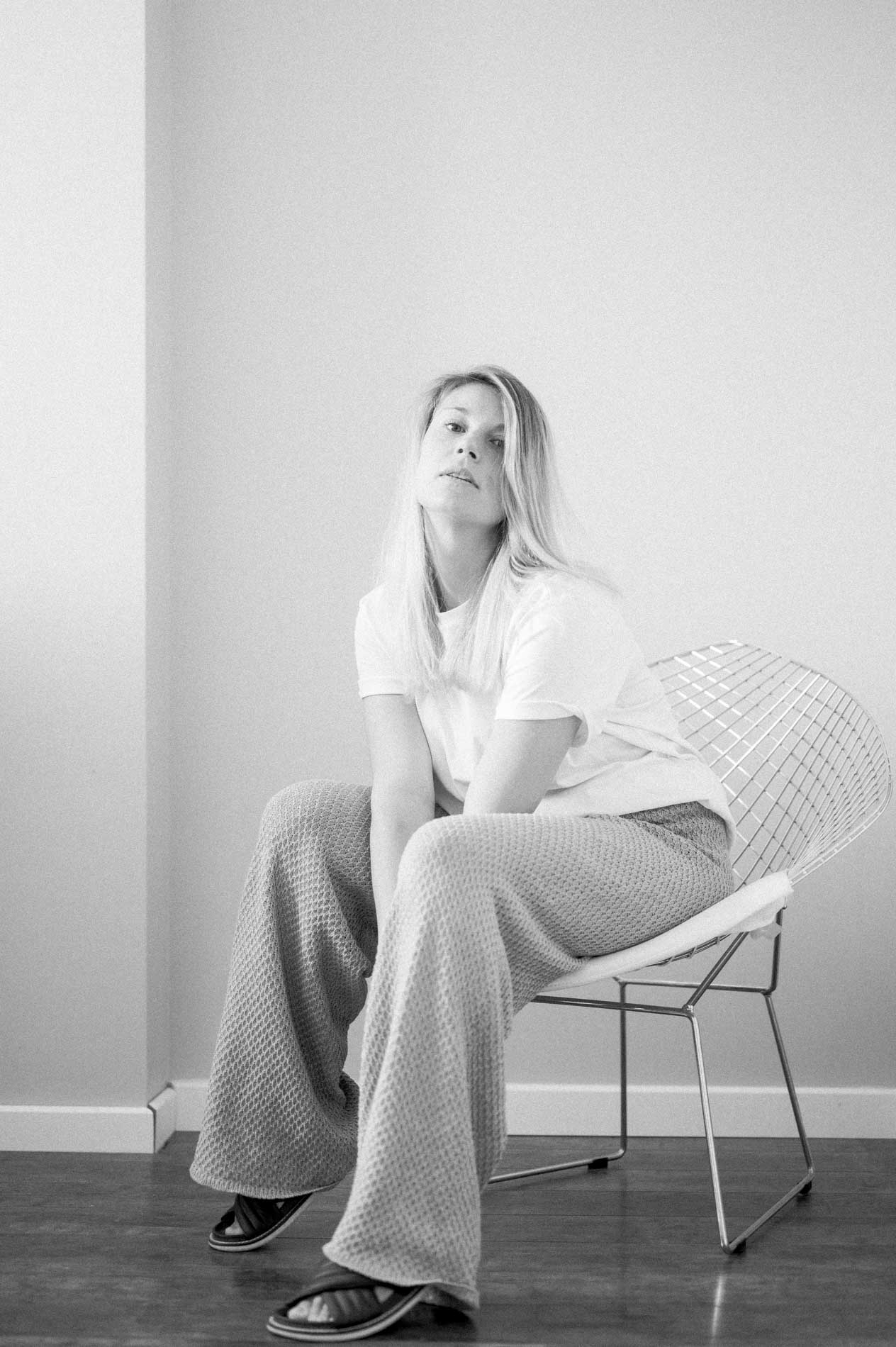 Mannequin assise sur une chaise en fil métallique, pantalon large, en noir et blanc