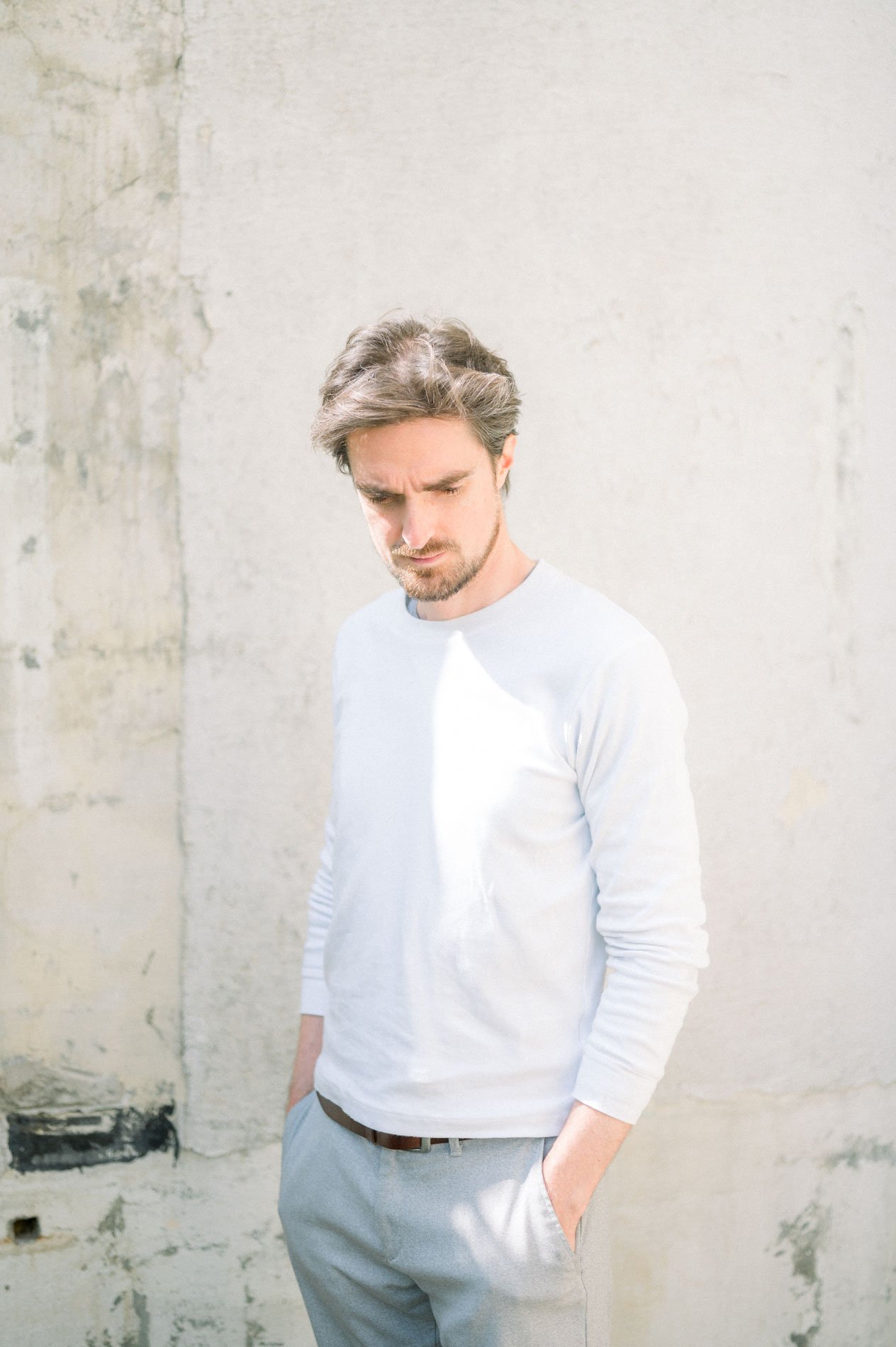 Mannequin homme en pull blanc devant un mur brut, séance mode Linesmanner