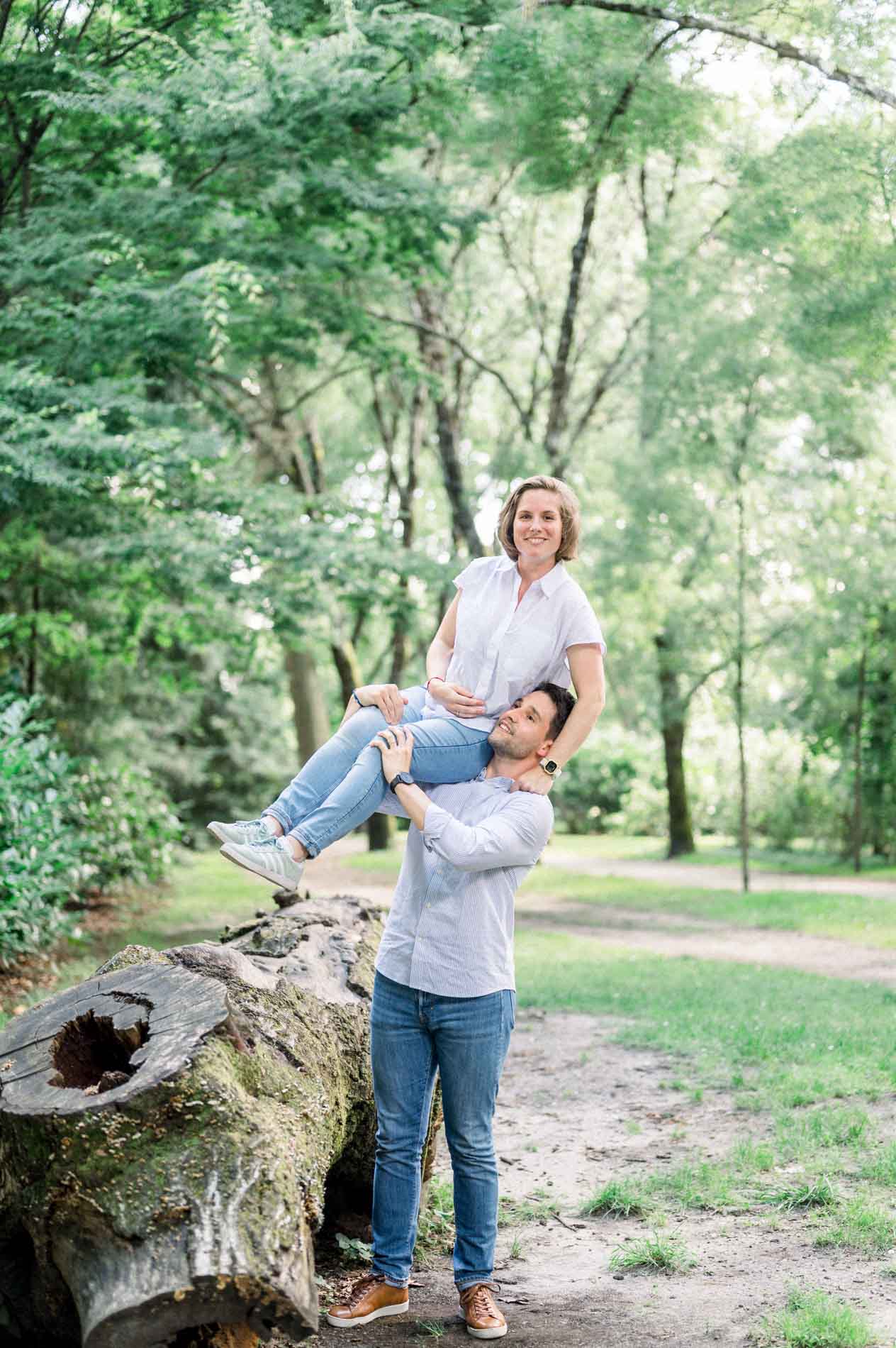 Future maman assise sur un tronc creux, son compagnon à ses côtés