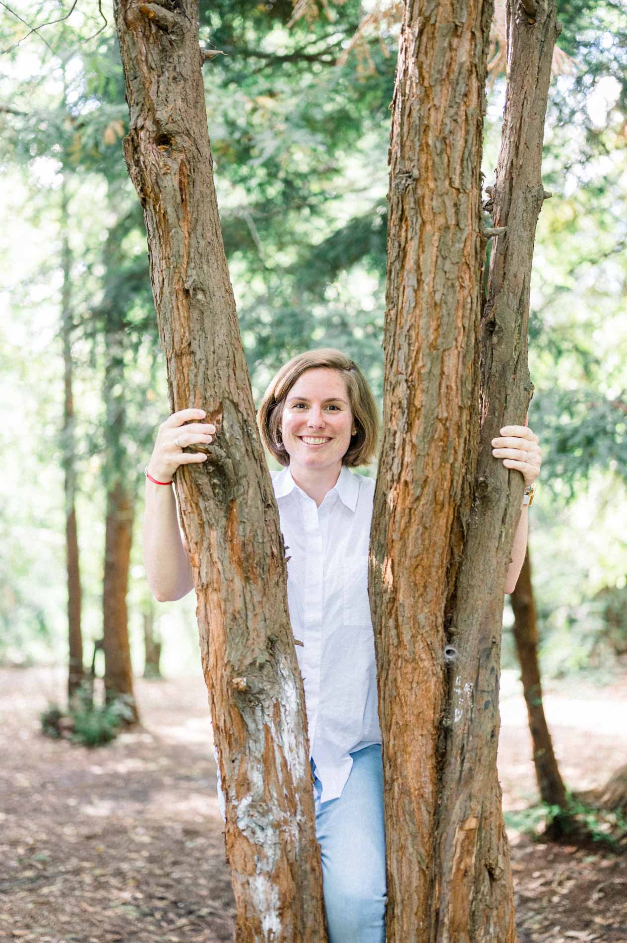 Future maman souriante entre deux troncs d'arbres