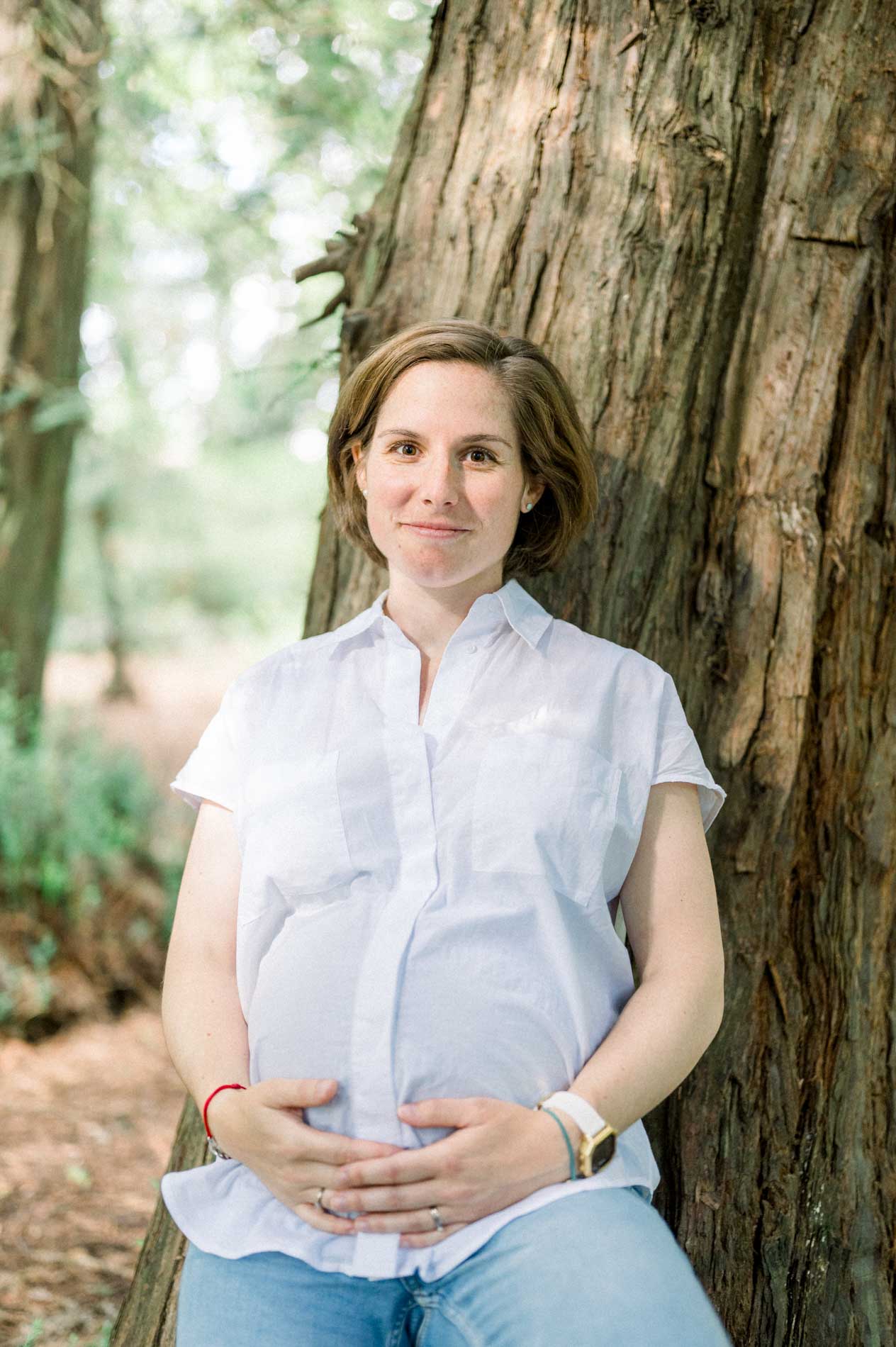 Portrait de grossesse, femme enceinte assise contre un tronc