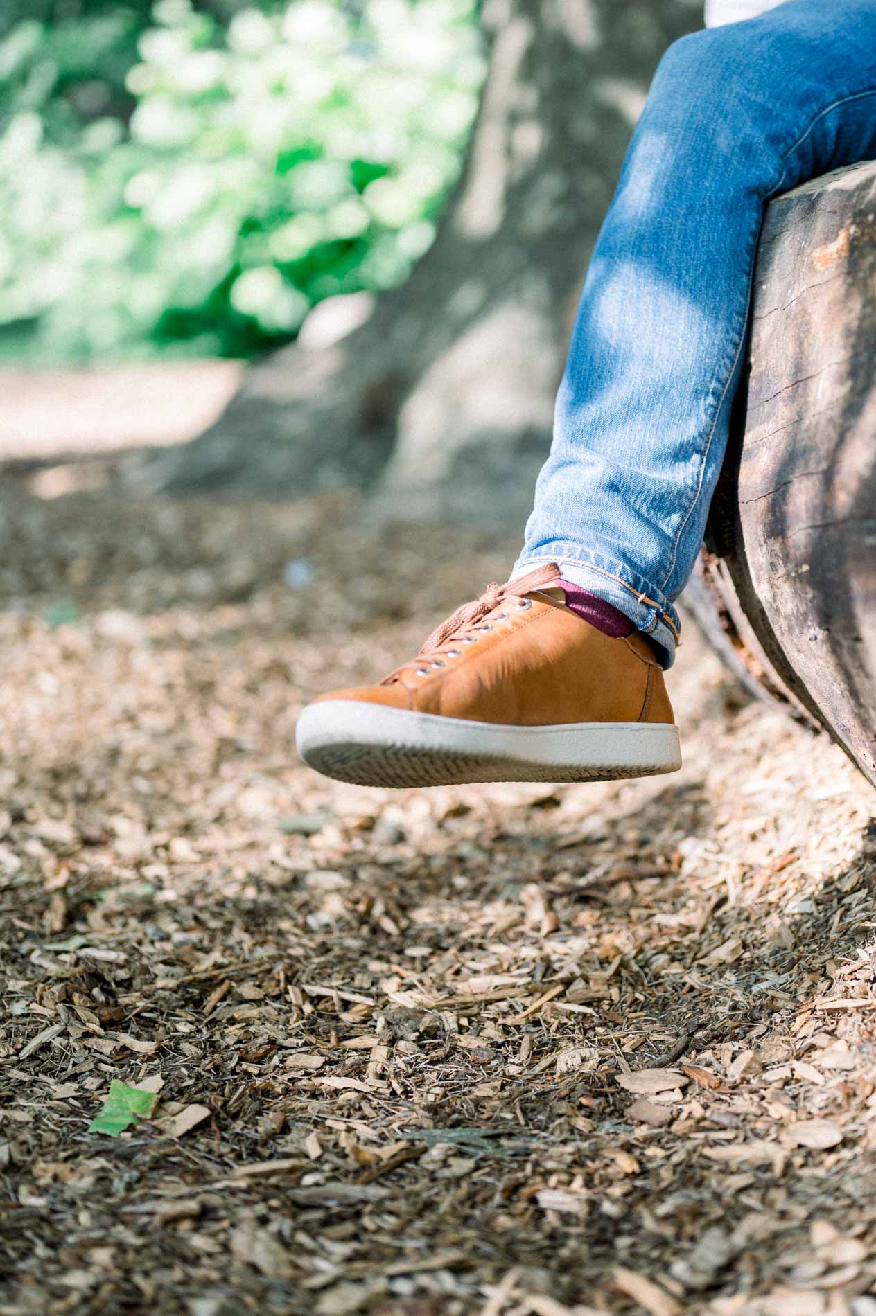 Détail des baskets et du jean du futur papa assis sur un tronc