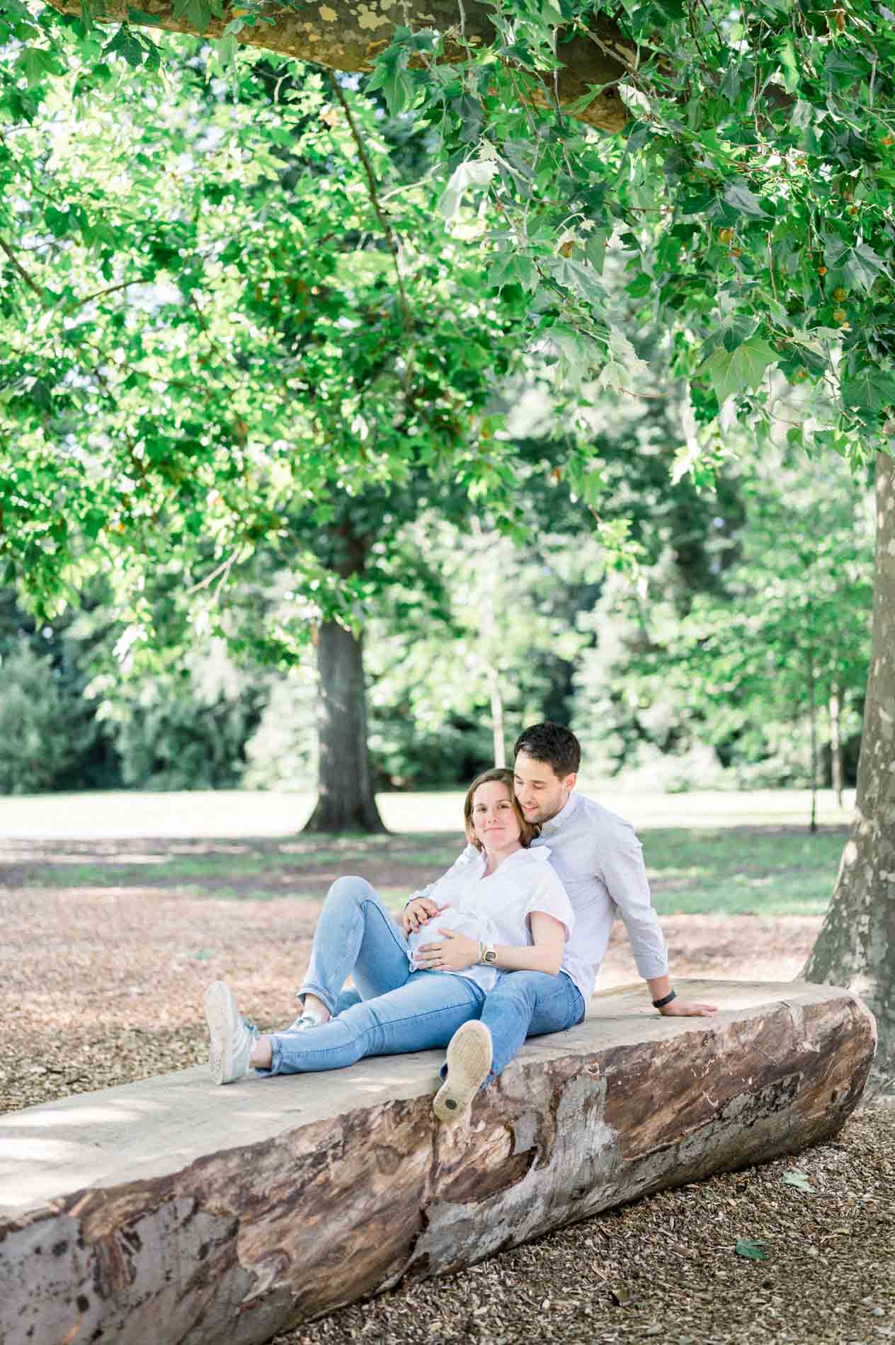 Couple assis sur un tronc couché à l'ombre des arbres du parc