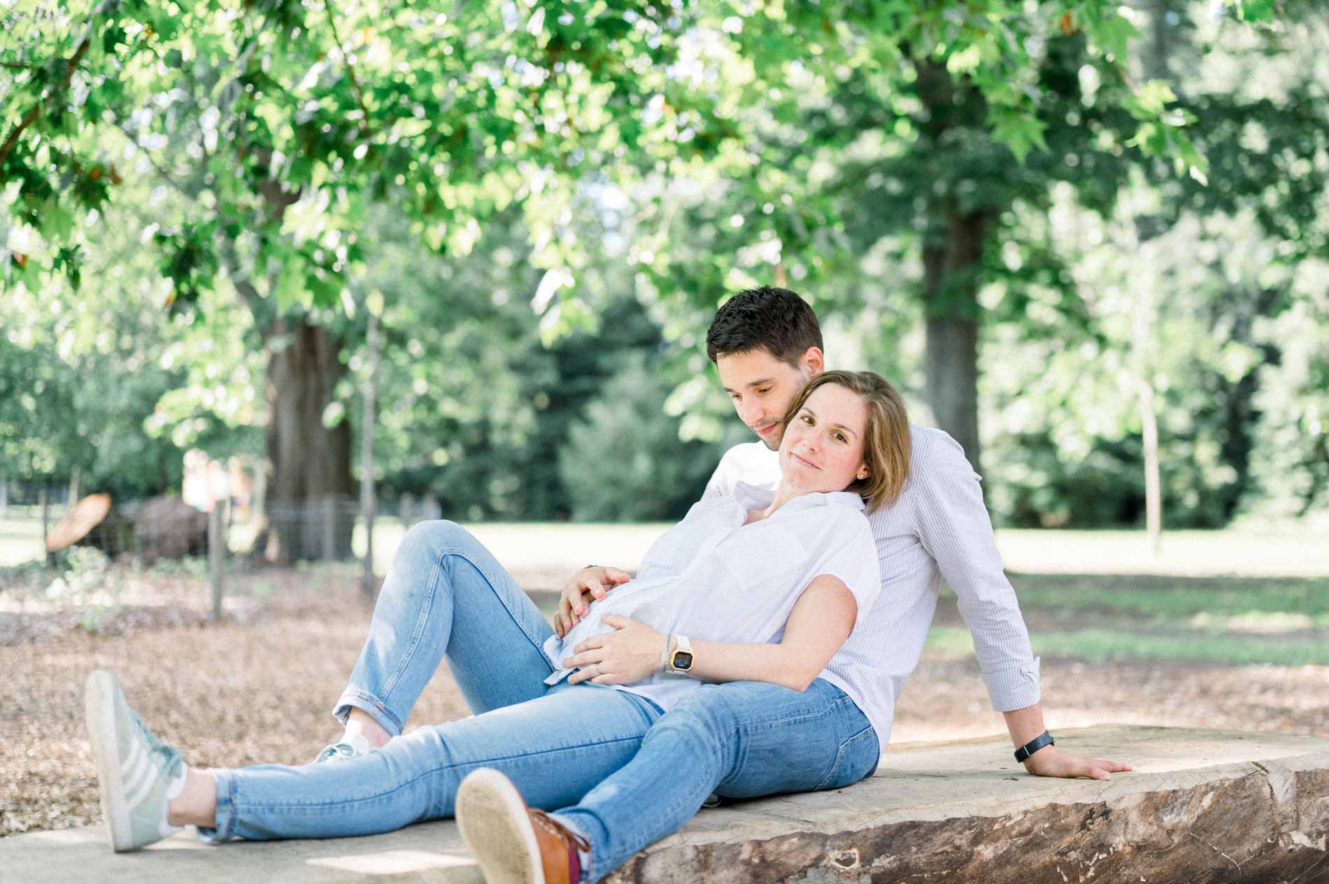 Futurs parents allongés sur un tronc d'arbre dans le parc
