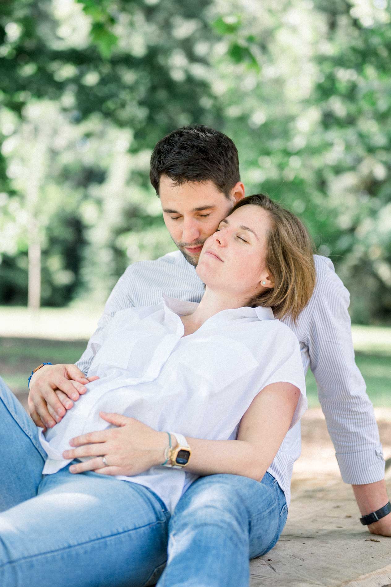 Future maman blottie contre son compagnon, mains sur son ventre rond