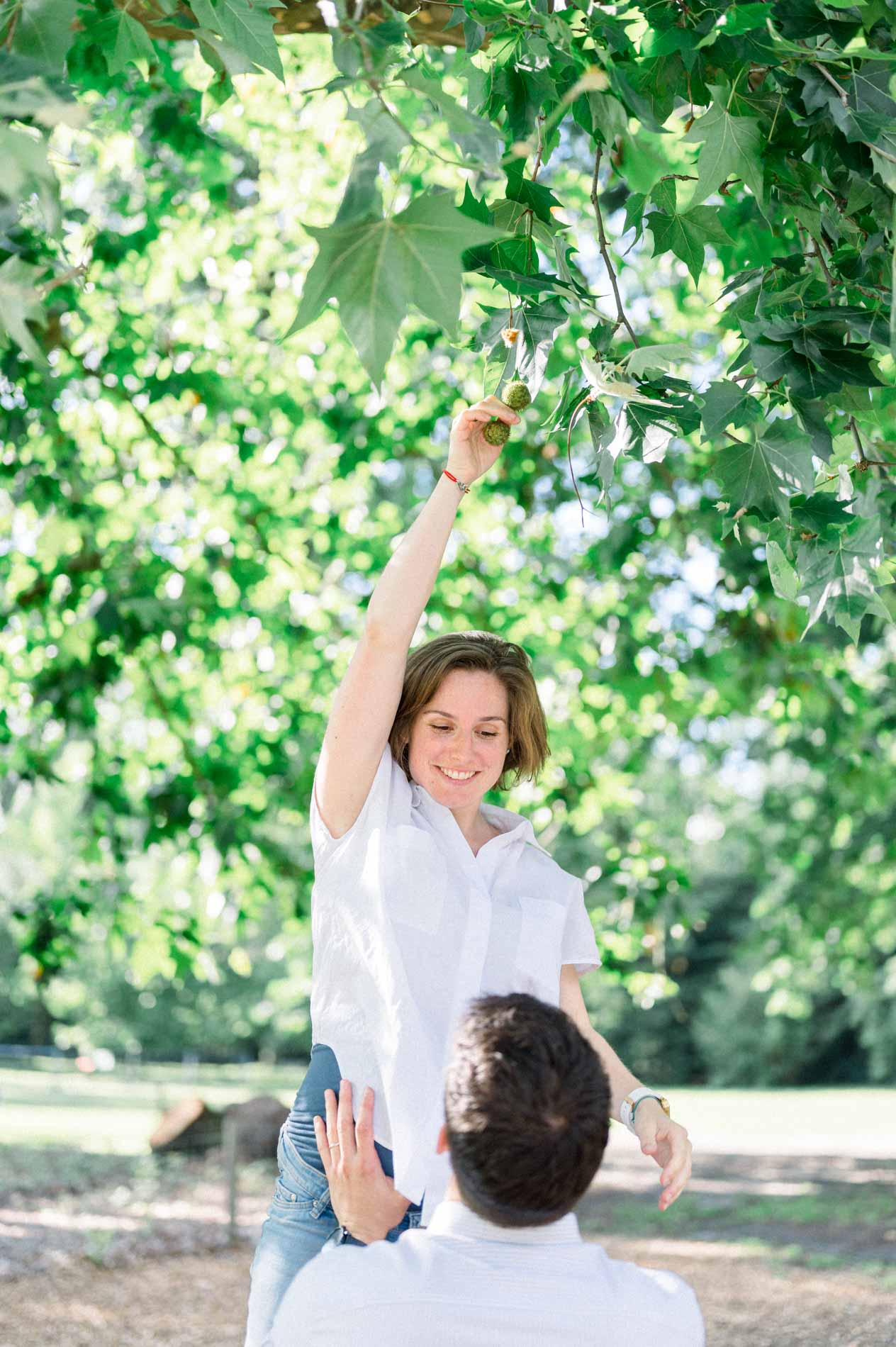 Future maman cueillant une feuille, son compagnon la regardant d'en bas
