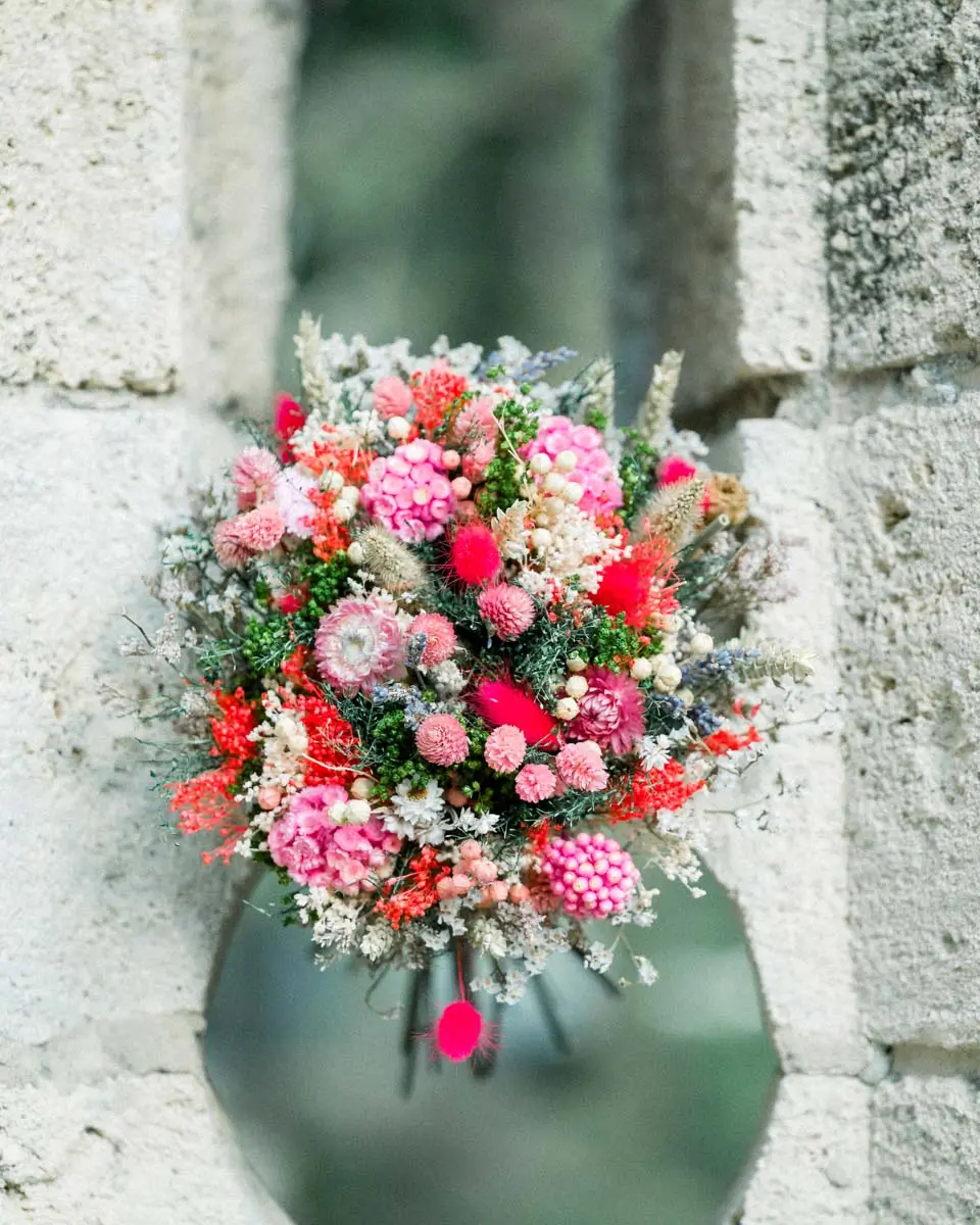 Bouquet de fleurs séchées posé dans une ouverture de pierre au Parc Majolan