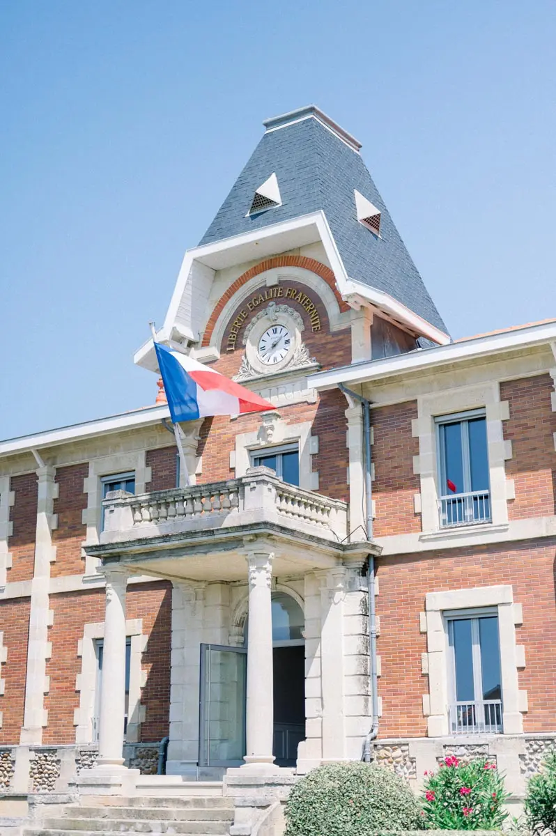Façade en briques et drapeau tricolore de la mairie de Soulac-sur-Mer le jour du mariage