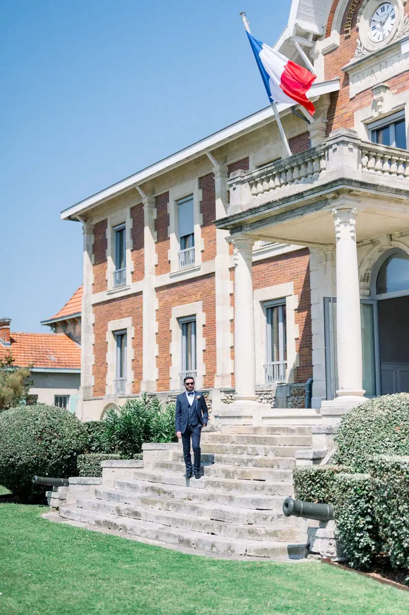 Le marié attend sur les marches de la mairie de Soulac-sur-Mer