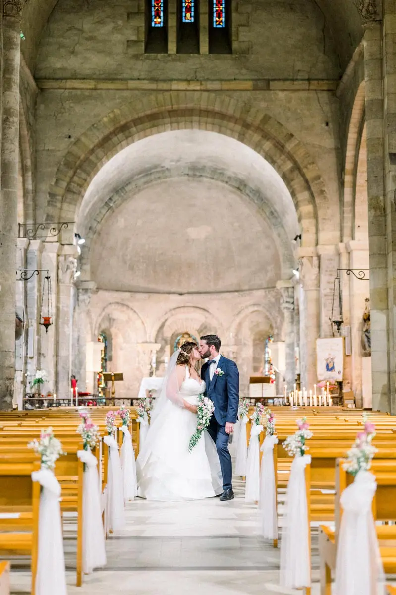 Les mariés s'embrassent dans l'allée de la basilique Notre-Dame-de-la-fin-des-Terres