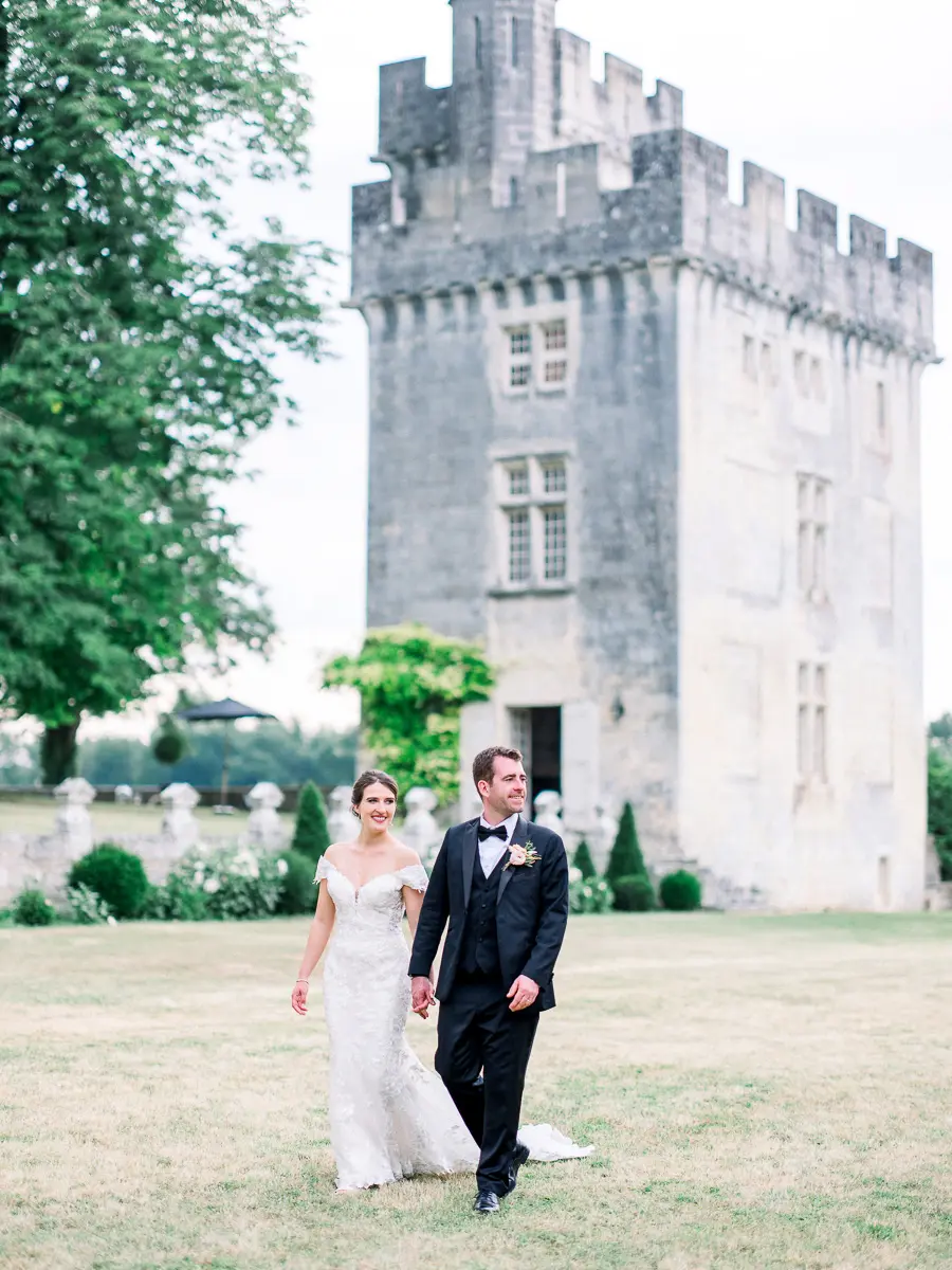 Mariés marchant devant le donjon du Château de Crazannes